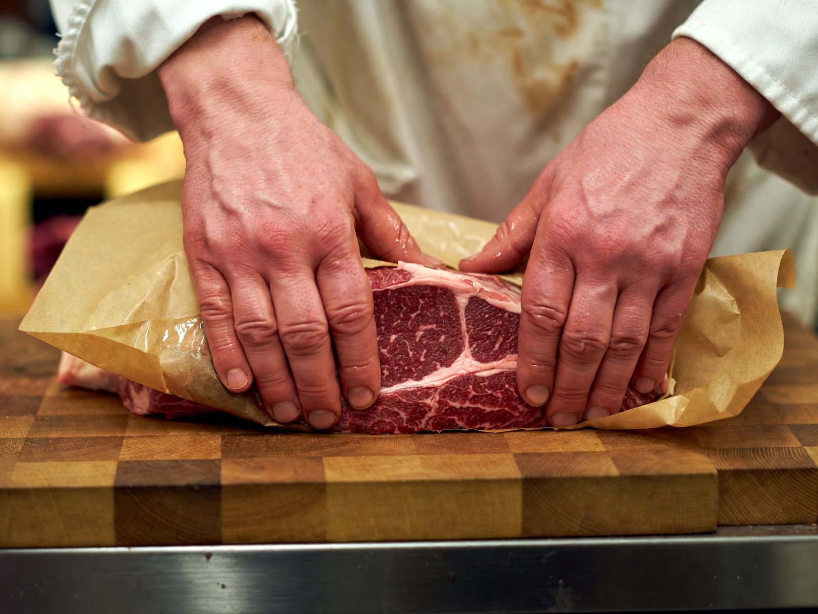 Metzger wickelt ein Steak in braunes Papier